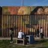 Voorbijgangers aan de gedeeltelijke grensmuur met de VS, in Playas de Tijuana, Mexico.